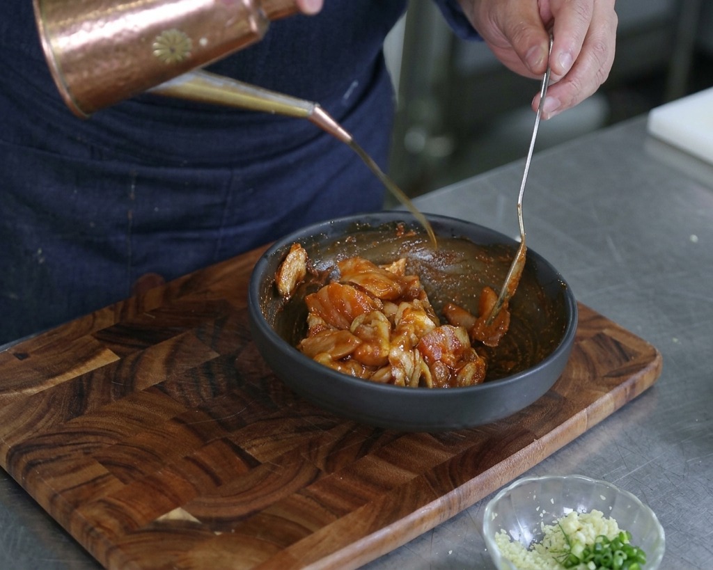 Mains versant un filet dhuile dolive depuis un huilier en cuivre sur les fruits de mer marinés.