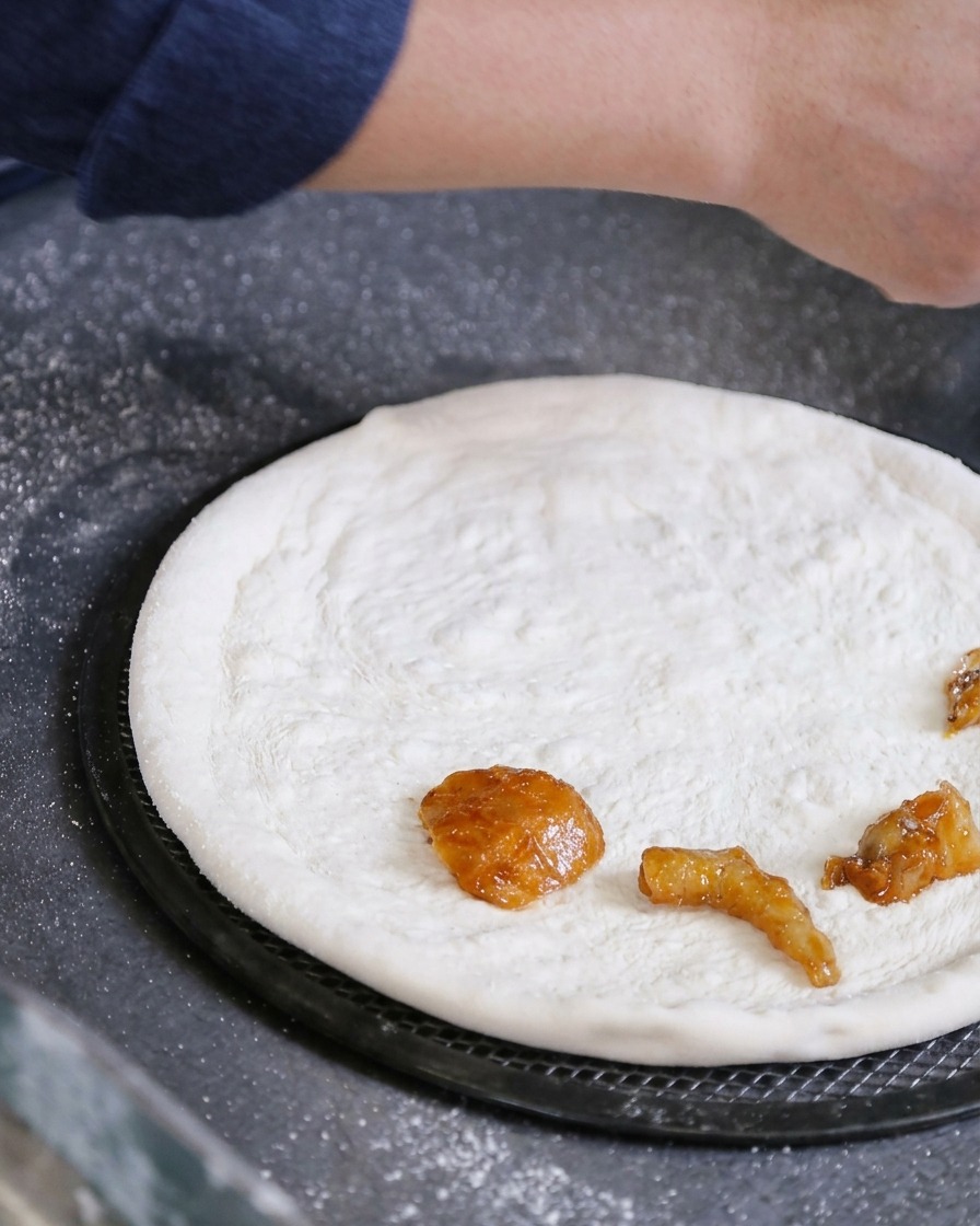 Main déposant des morceaux de fruits de mer marinés directement sur la pâte à pizza étalée.