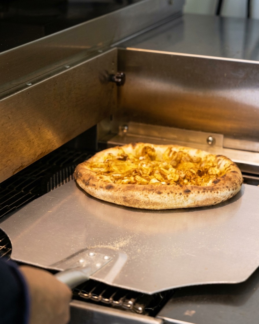 Pizza aux fruits de mer cuite avec une croûte dorée retirée du four à laide dune pelle à pizza en métal.