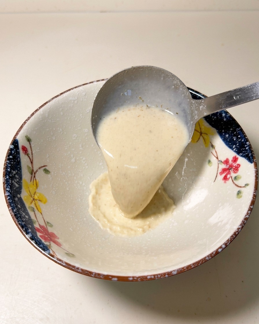 Une louche versant la base de soupe crémeuse et chaude dans un bol en céramique décoré.