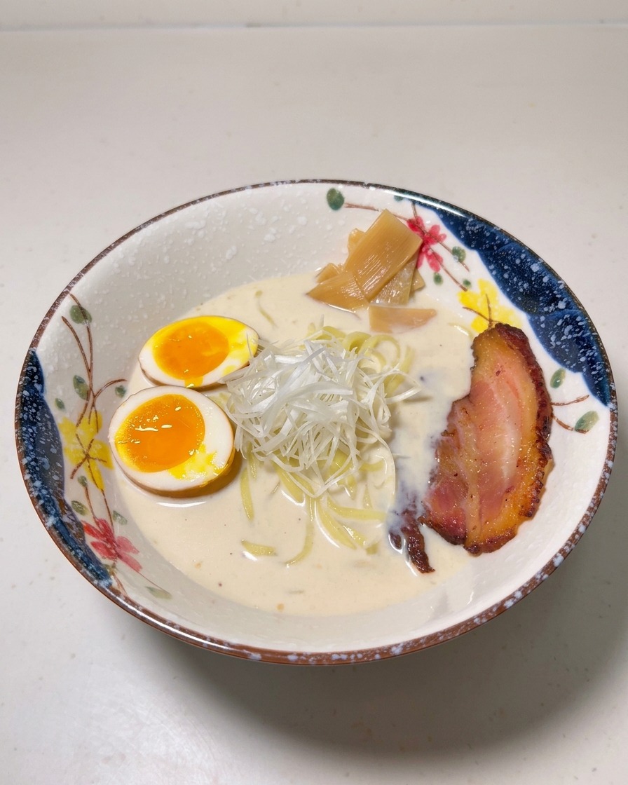 Bol de ramen garni dœufs mollets, de pousses de bambou, doignons verts et dune tranche de porc chashu grillée.