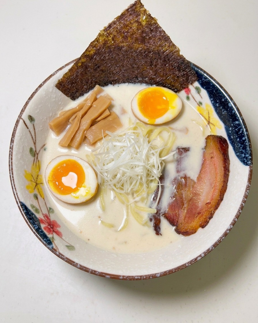 Une feuille dalgue nori sombre insérée sur le côté dun bol de ramen bien garni.