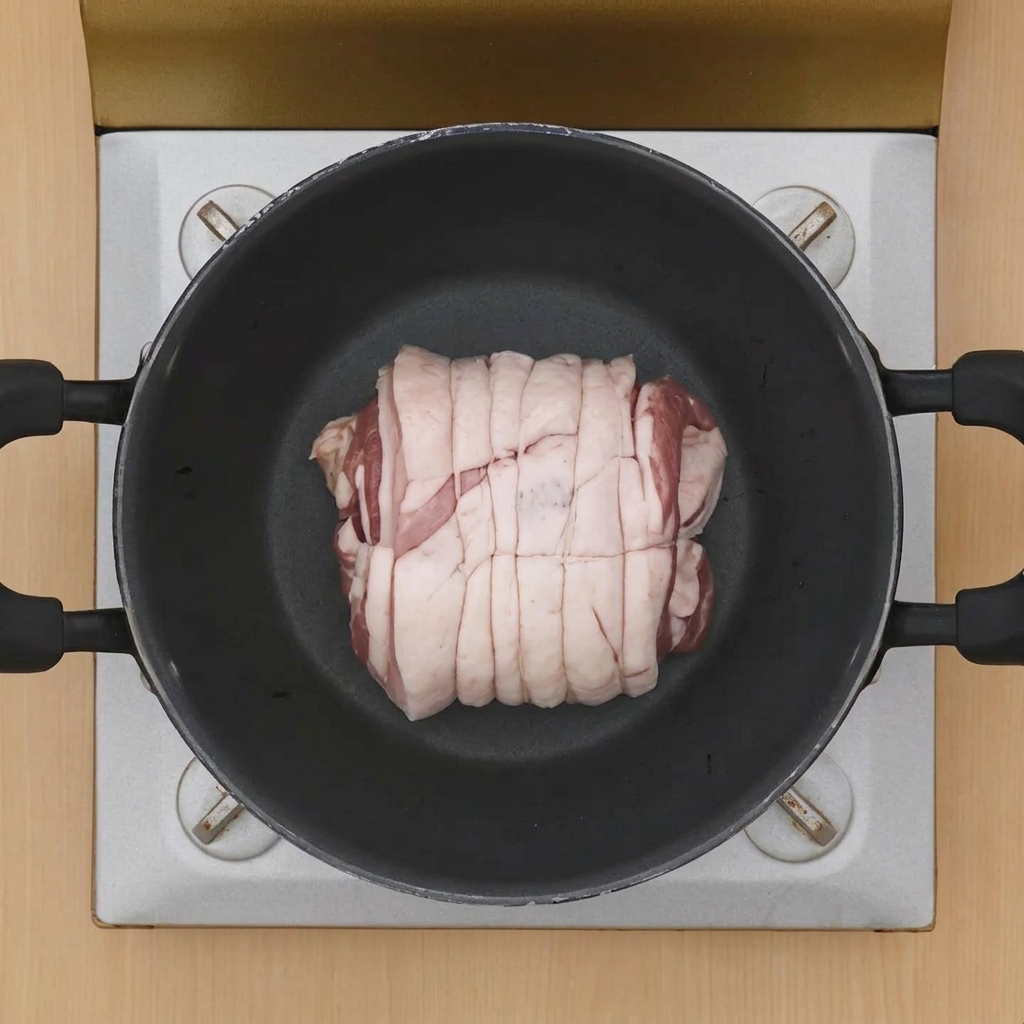 Un rouleau de porc ficelé et pâle placé au centre dune cocotte chaude pour la cuisson.