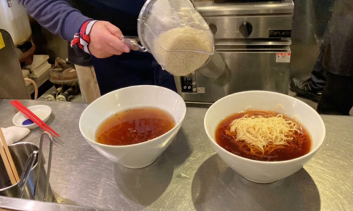 Nouilles ramen fraîches versées de la passoire dans un bol de soupe chaude.