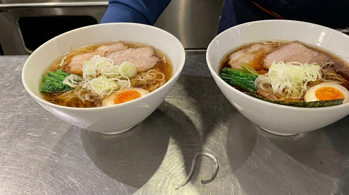 Une feuille de nori carrée glissée sur le bord dun bol de ramen fumant.
