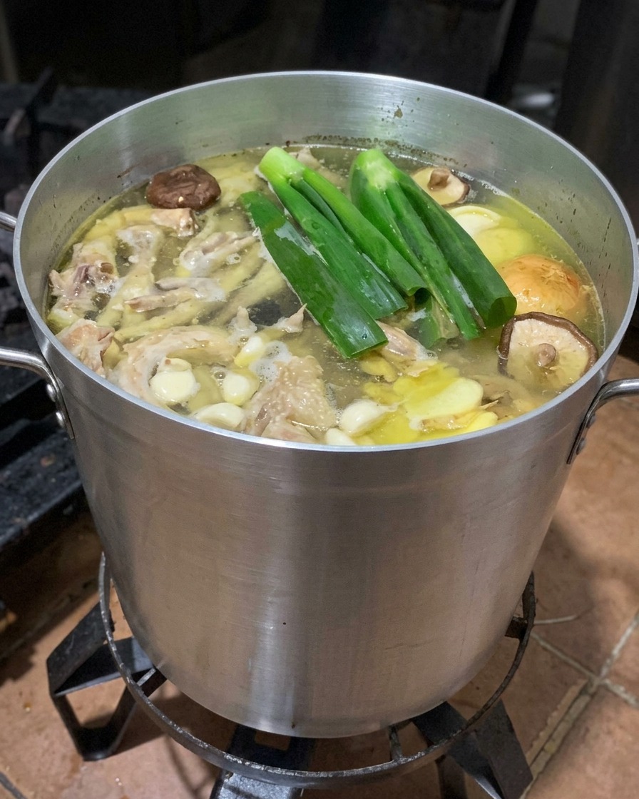 Marmite de bouillon en ébullition avec oignons verts, gingembre, shiitakes et demi-pommes.