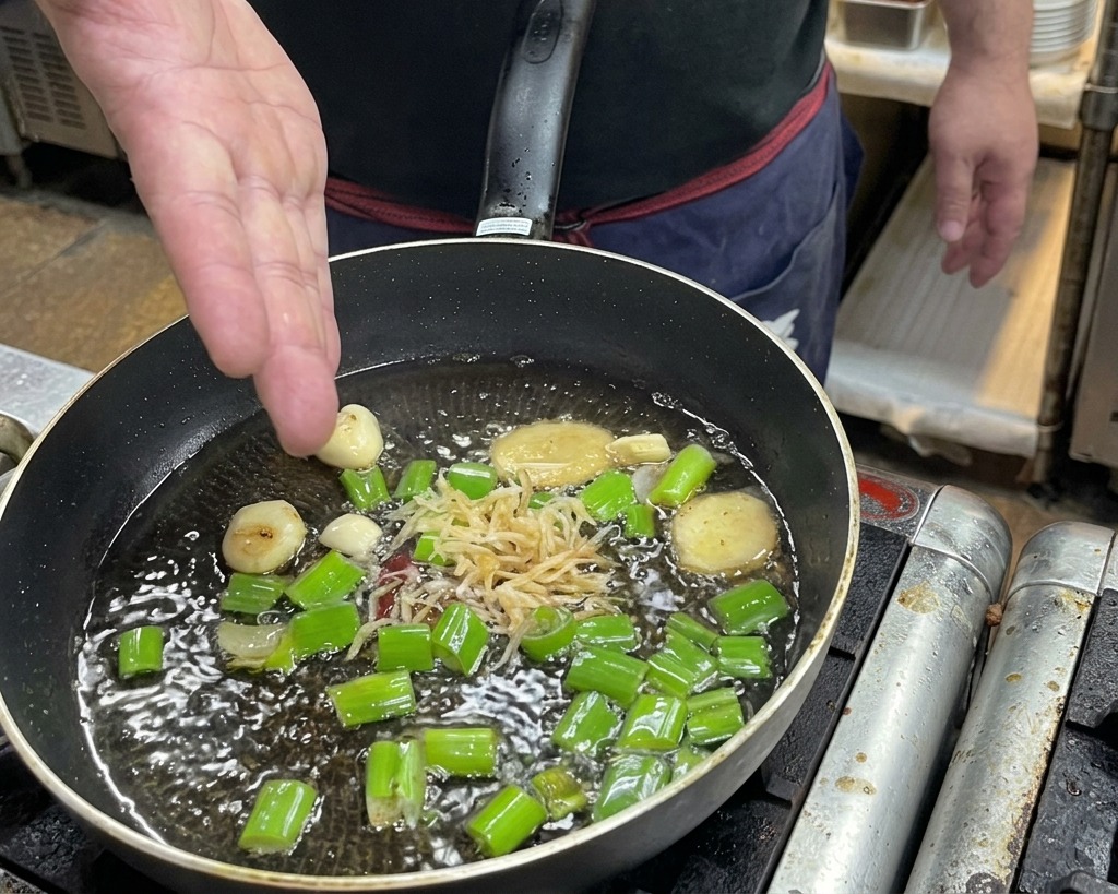 Une main jetant des crevettes séchées dans la poêle dhuile chaude avec les aromates.