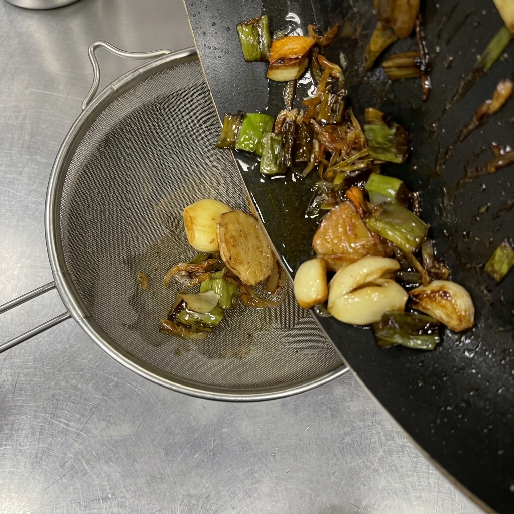 Verser lhuile chaude et les aromates brunis dans une passoire fine.