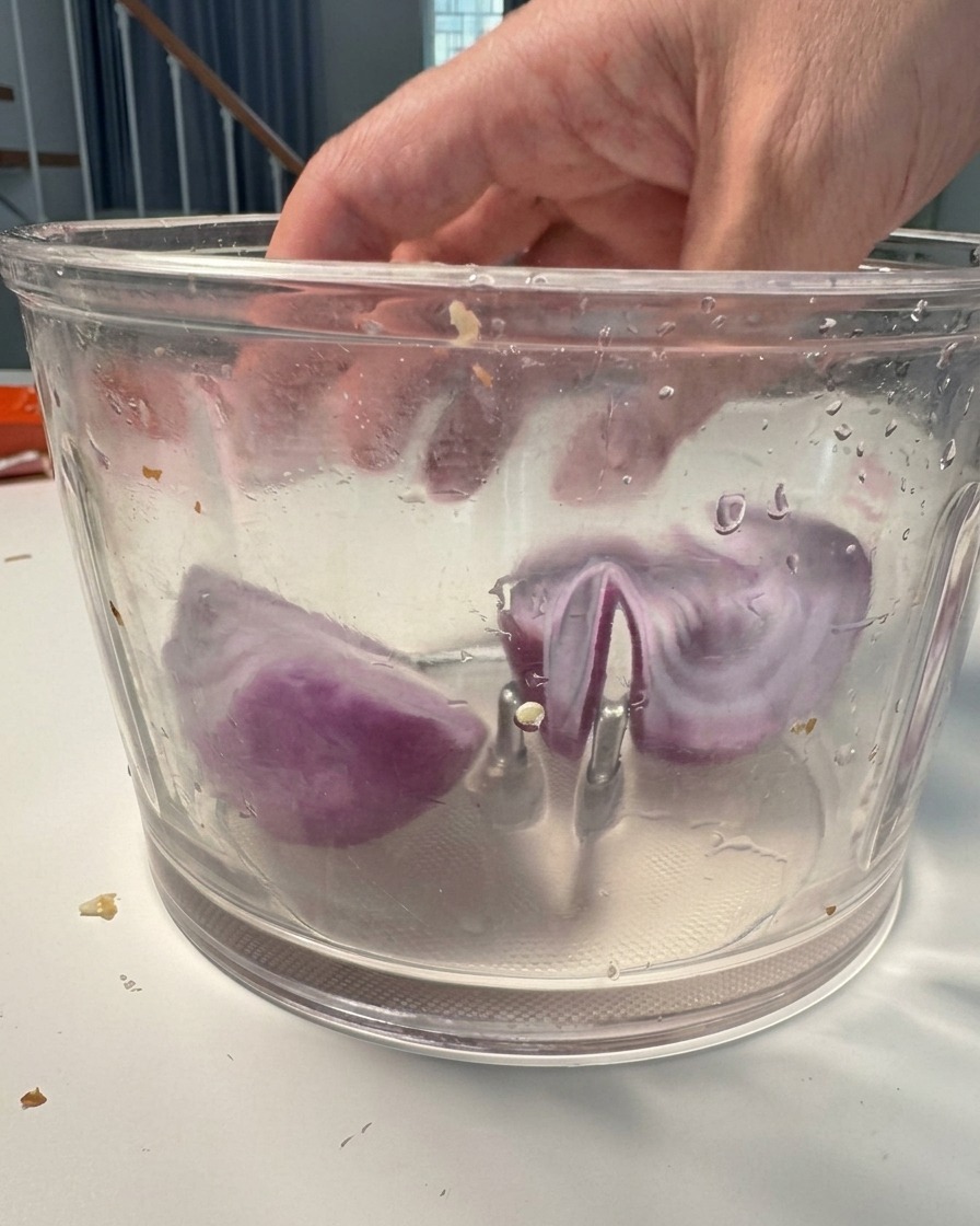 Gros morceaux doignon rouge dans un robot culinaire prêts à être mixés.