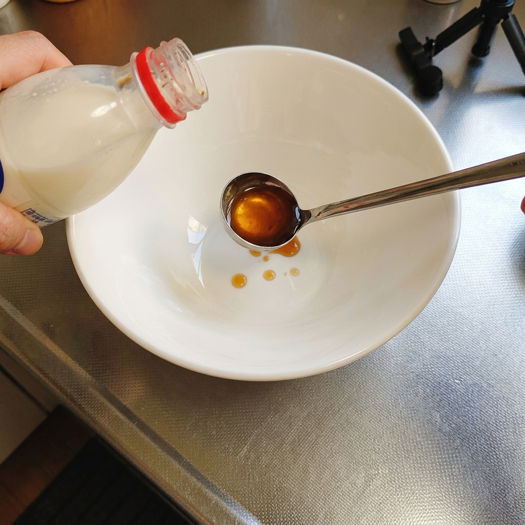 Versement de lassaisonnement tare liquide de couleur ambrée dune bouteille dans une louche au-dessus dun bol blanc.