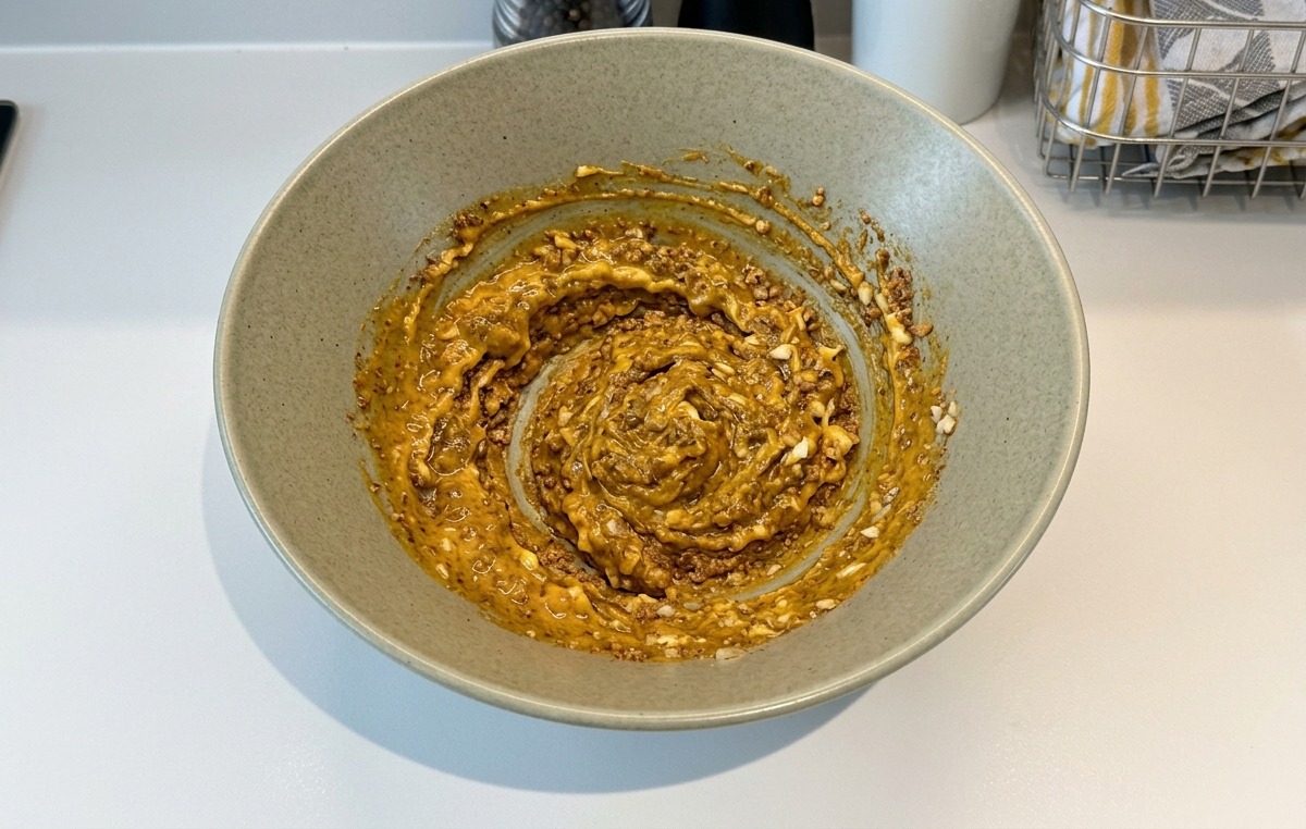 Une pâte épaisse et lisse de condiments, mayonnaise et ail mélangée à lintérieur dun bol en céramique.