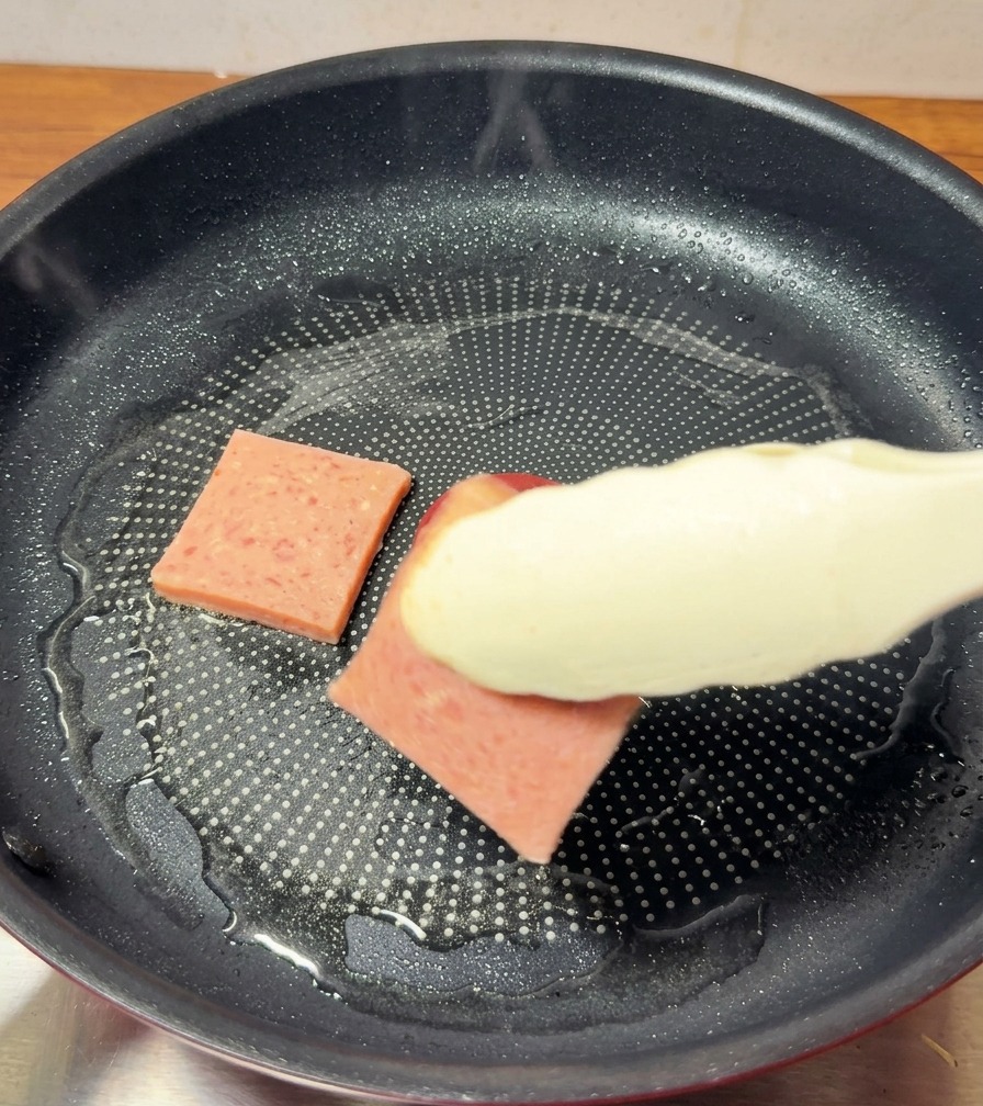 Tranches de jambon dorant dans une poêle antiadhésive.