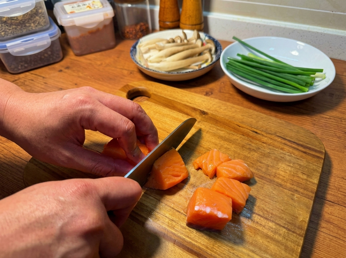 Mains découpant un filet de saumon cru en morceaux réguliers sur une planche à découper.