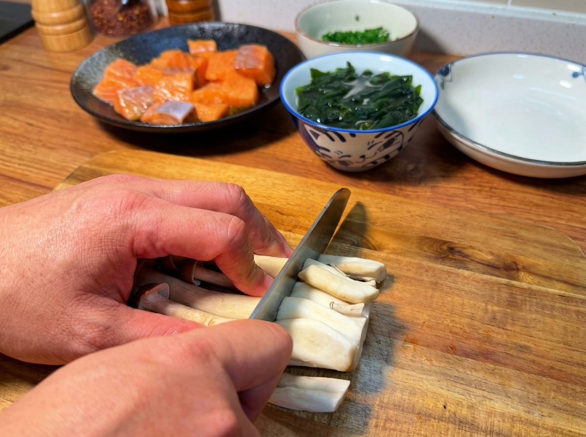 Mains coupant la base des champignons shimeji sur une planche à découper en bois.