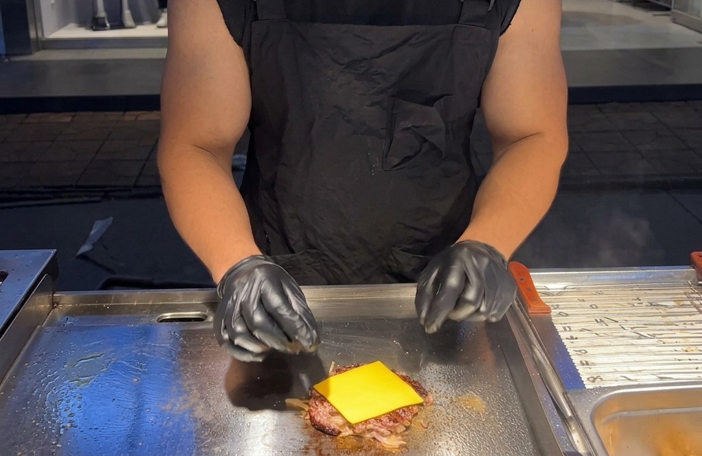 Une tranche carrée de fromage américain jaune posée sur un steak de bœuf chaud sur la plaque.