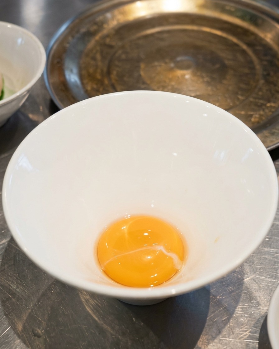 Une petite quantité de sauce tare au sel jaune doré au fond dun bol à ramen en céramique blanche vide.