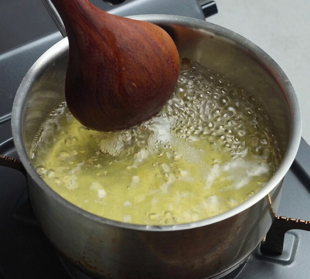 Bouillon frémissant dans une casserole, remué doucement avec une cuillère en bois.