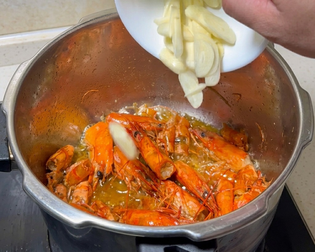 Ail fraîchement émincé ajouté dans la marmite contenant les carapaces de crevettes frites.