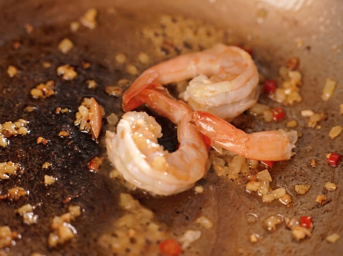 Crevettes sautées dans une poêle avec des miettes de jaune dœuf salé jaune vif.