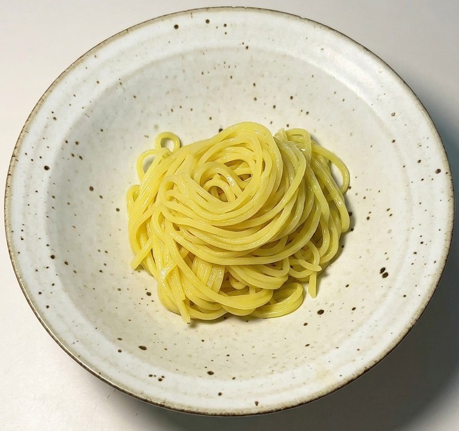 Un nid de nouilles ramen jaunes disposé au centre dun bol en céramique blanche.