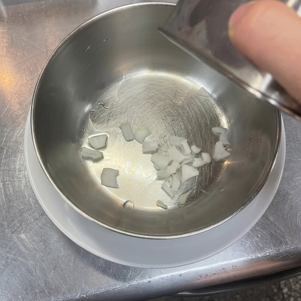 Petits morceaux doignon blanc émincé au fond dun bol à mélanger propre en acier inoxydable.