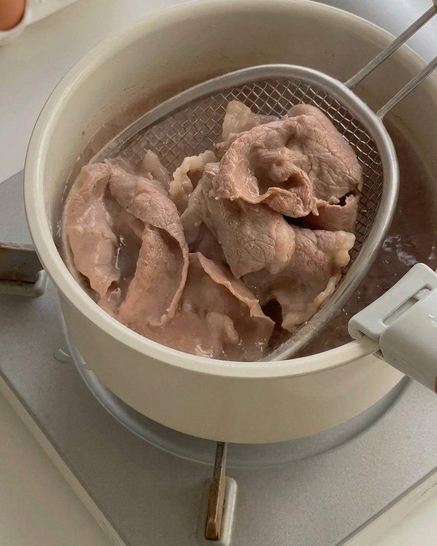 Tranches de bœuf cuites retirées dune casserole deau bouillante à laide dune araignée de cuisine.