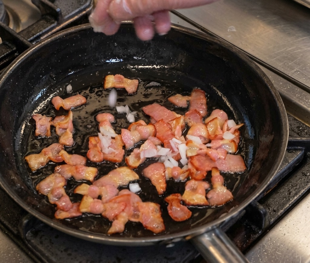 Ajout doignons en dés dans une poêle de bacon en train de frire.