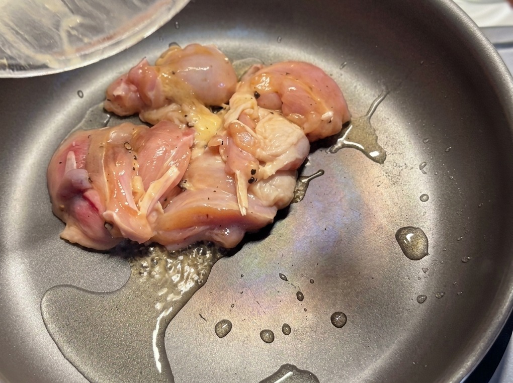 Morceaux de poulet mariné saisis dans une poêle chaude avec un léger filet dhuile.