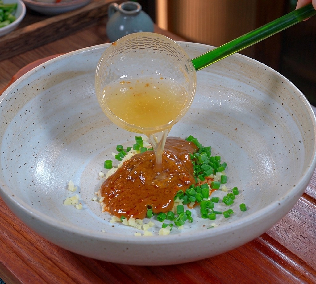 Graisse de porc liquide et dorée versée dune louche verte translucide dans un bol dassaisonnement.