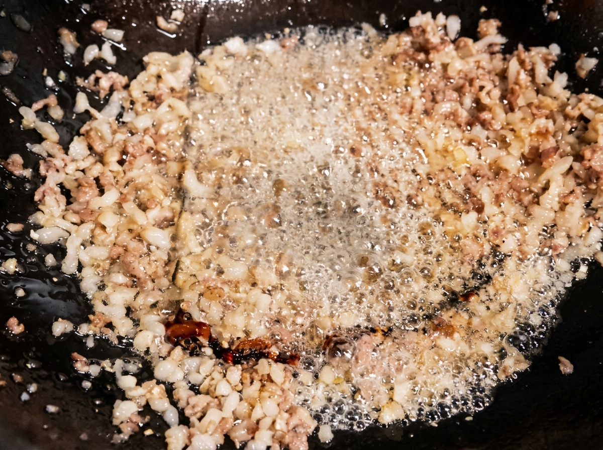 Sauce soja claire versée sur la viande hachée dans le wok, lassaisonnement bouillonnant dans lhuile chaude.