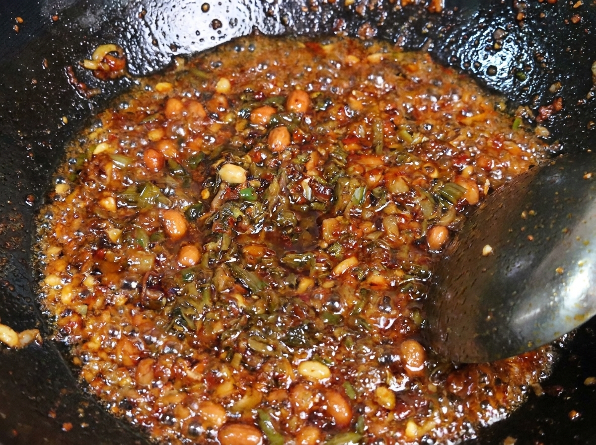 Un mélange de porc haché assaisonné et de pousses de moutarde marinées foncées sautées ensemble dans un wok.