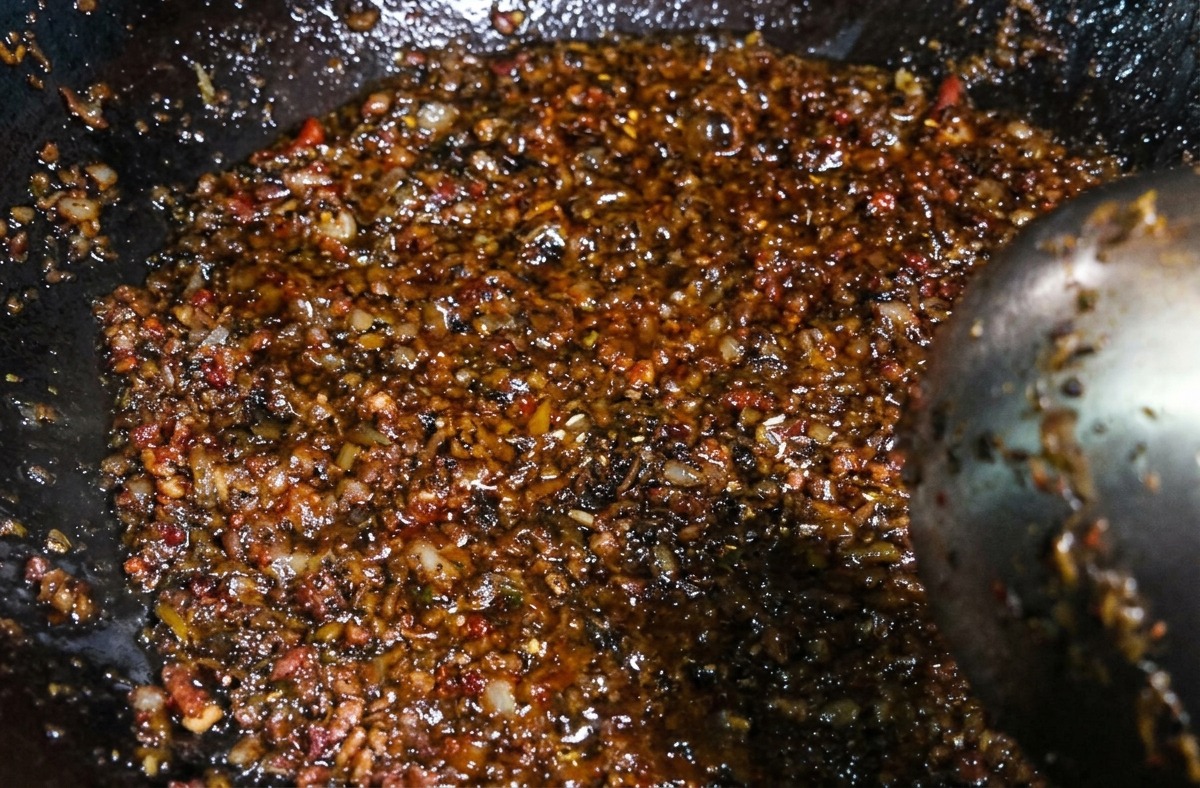 Un mélange sombre et savoureux de viande hachée et de légumes marinés remué avec une louche après lajout des épices.