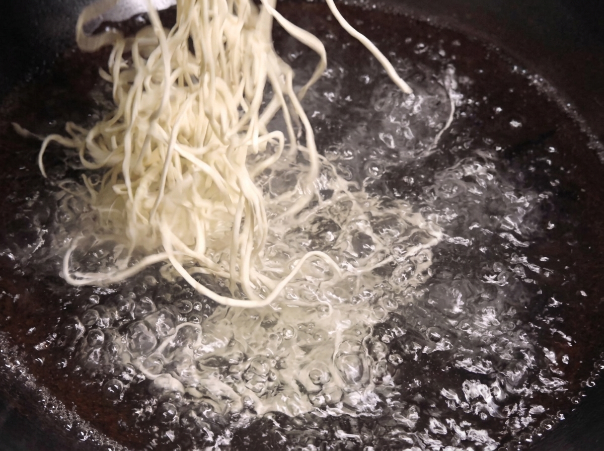 Un nid de nouilles blanches et fraîches plongé dans une grande marmite deau bouillante.