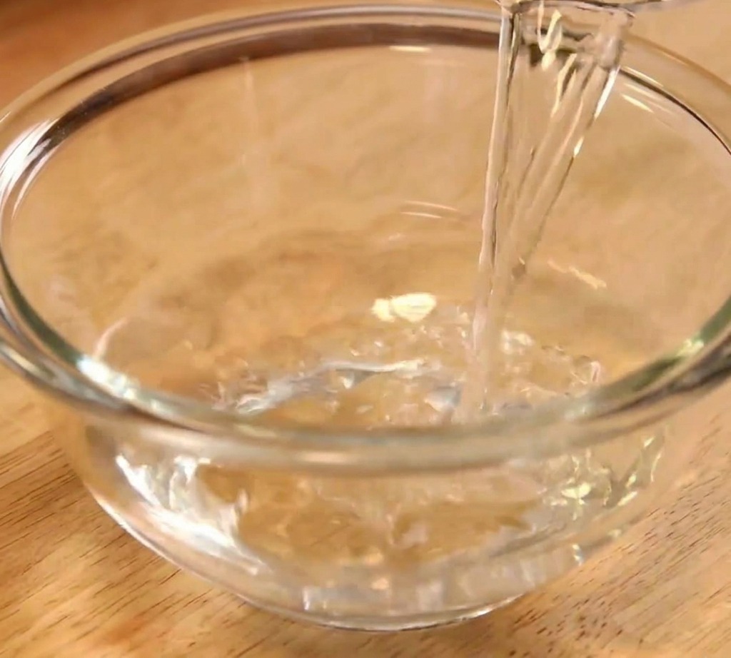 De leau claire versée dans un bol mélangeur en verre transparent pour la préparation de la sauce.