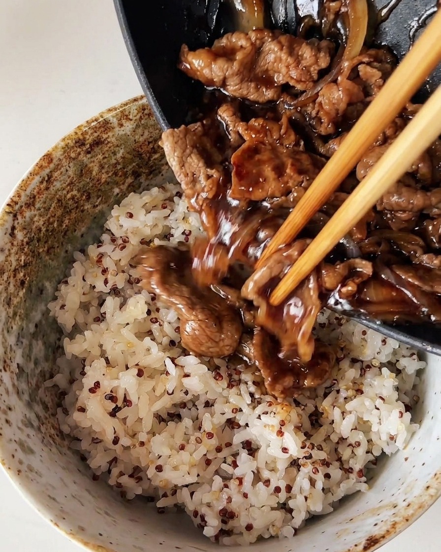 Du bœuf et des oignons cuisinés en sauce sont versés depuis une poêle sur un bol de riz blanc cuit à la vapeur mélangé à du quinoa.