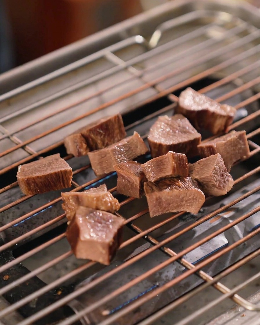 Plusieurs morceaux de langue de bœuf épais sur une grille métallique, luisants sous une couche de sauce brun foncé.