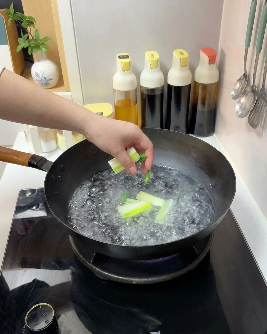 Une main jetant des morceaux doignons verts coupés dans un wok deau bouillante.