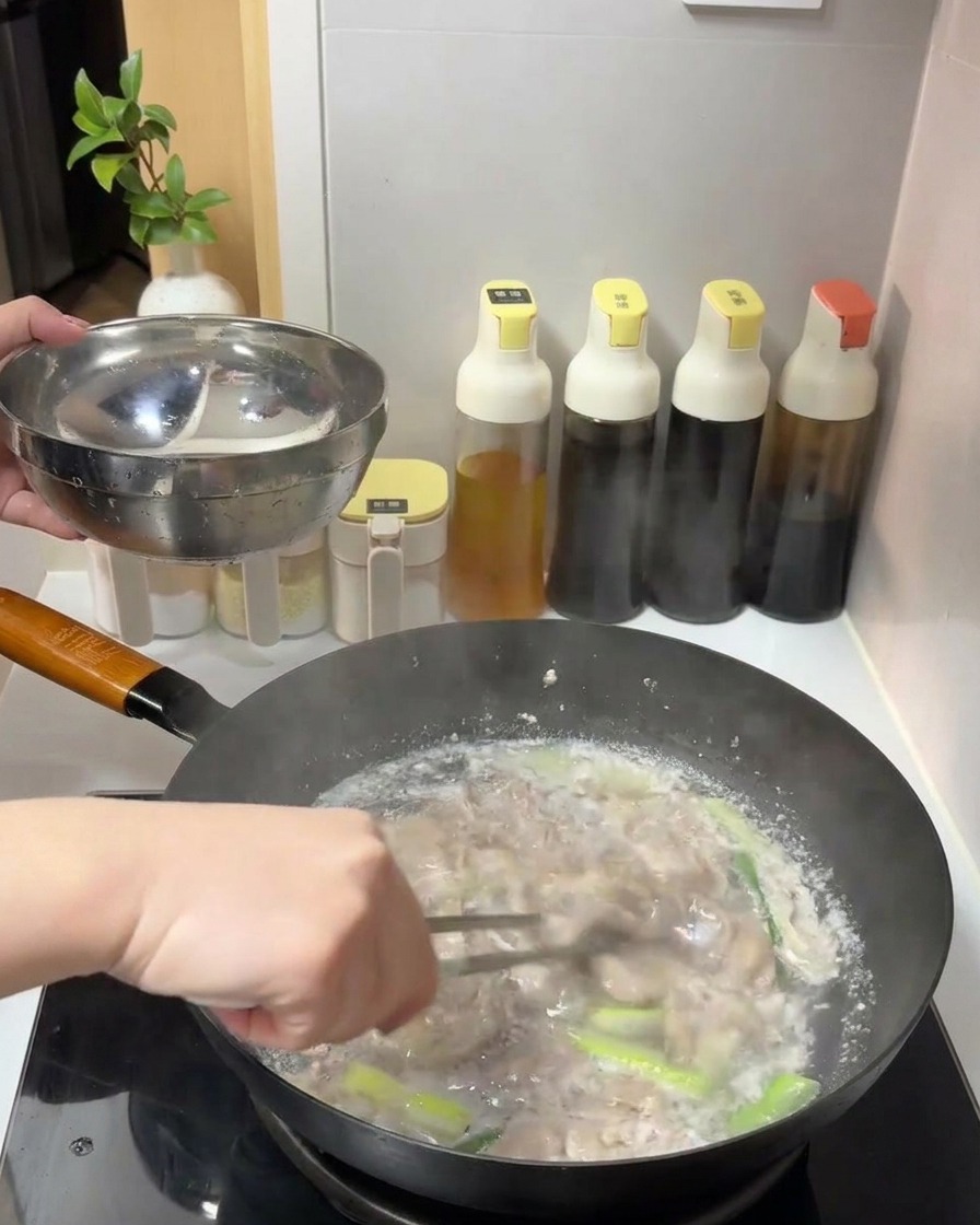 Tranches de bœuf cuites retirées dune casserole deau frémissante avec une pince et déposées dans un bol en métal.