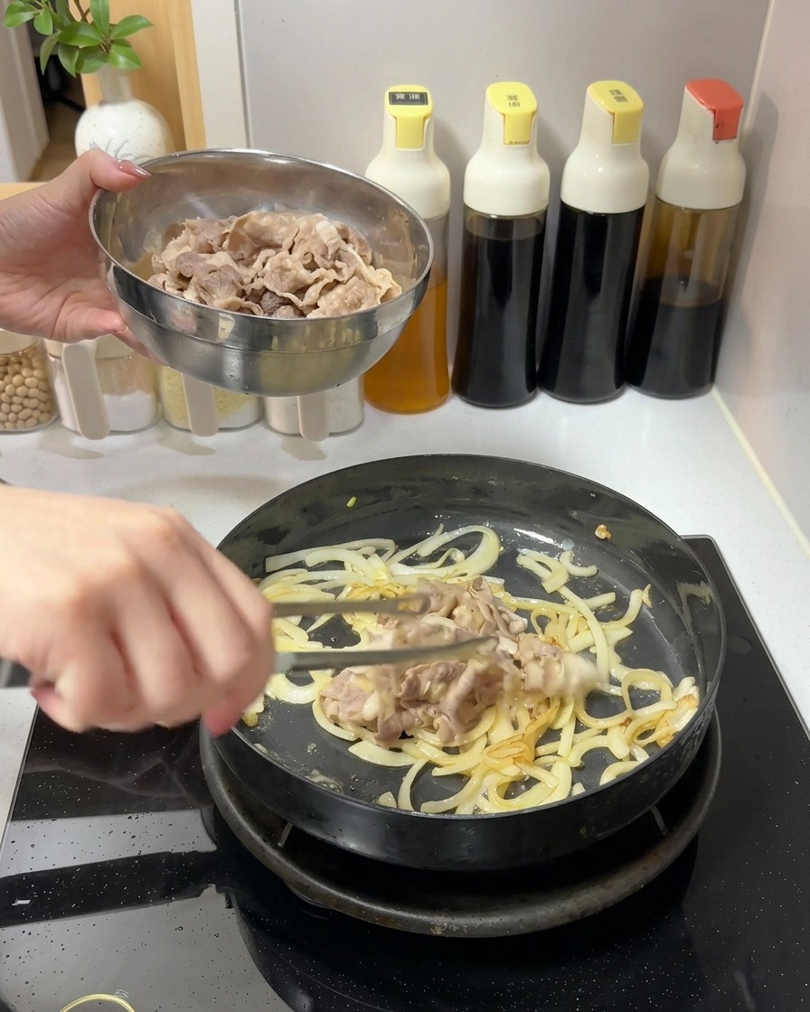 Ajout dun bol de tranches de bœuf cuites dans une poêle contenant les oignons sautés.