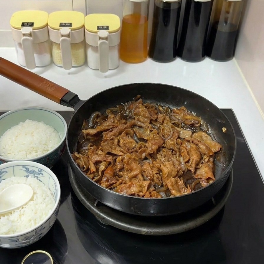 Fines tranches de bœuf et oignons mijotant dans une sauce soja sombre et parfumée dans une poêle noire sur une plaque à induction.