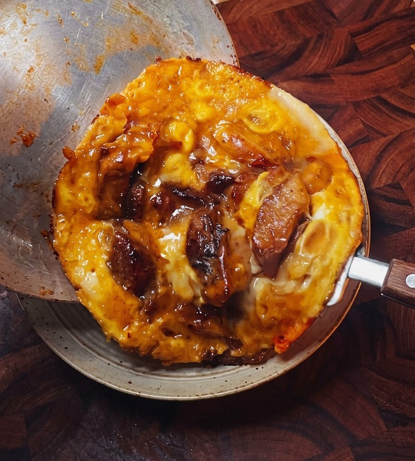 La garniture dœufs et de poulet cuits glissant doucement dune poêle en métal vers un bol de riz blanc bien chaud.