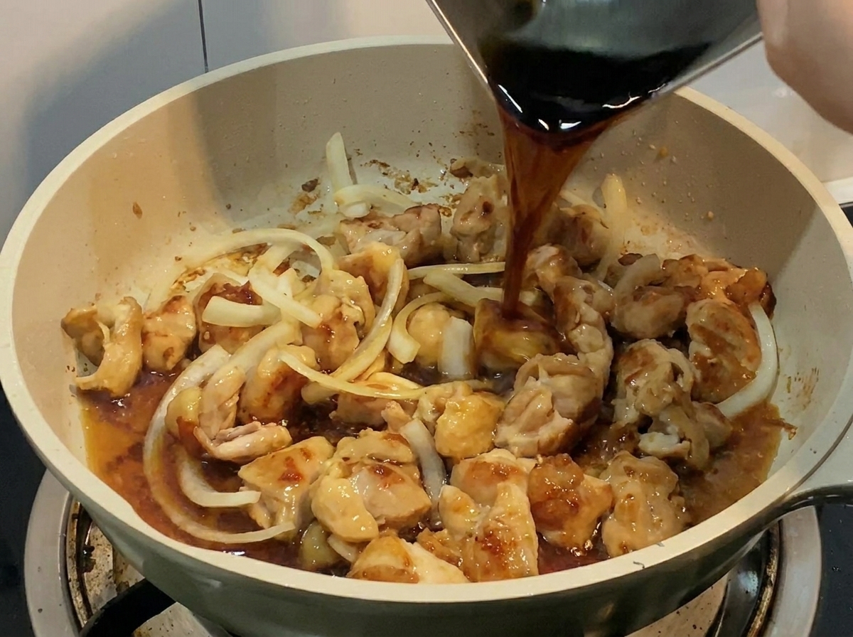 Un liquide sombre et savoureux versé depuis un récipient métallique dans la poêle contenant le poulet et les oignons.