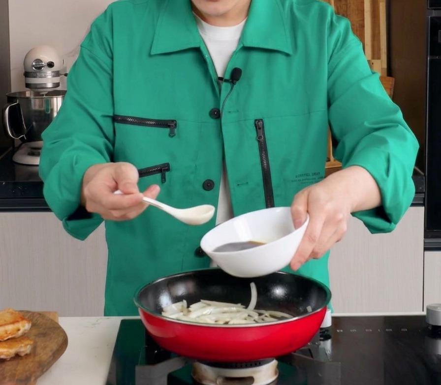 Une sauce brune savoureuse versée depuis un bol blanc dans une poêle contenant des oignons fondants.