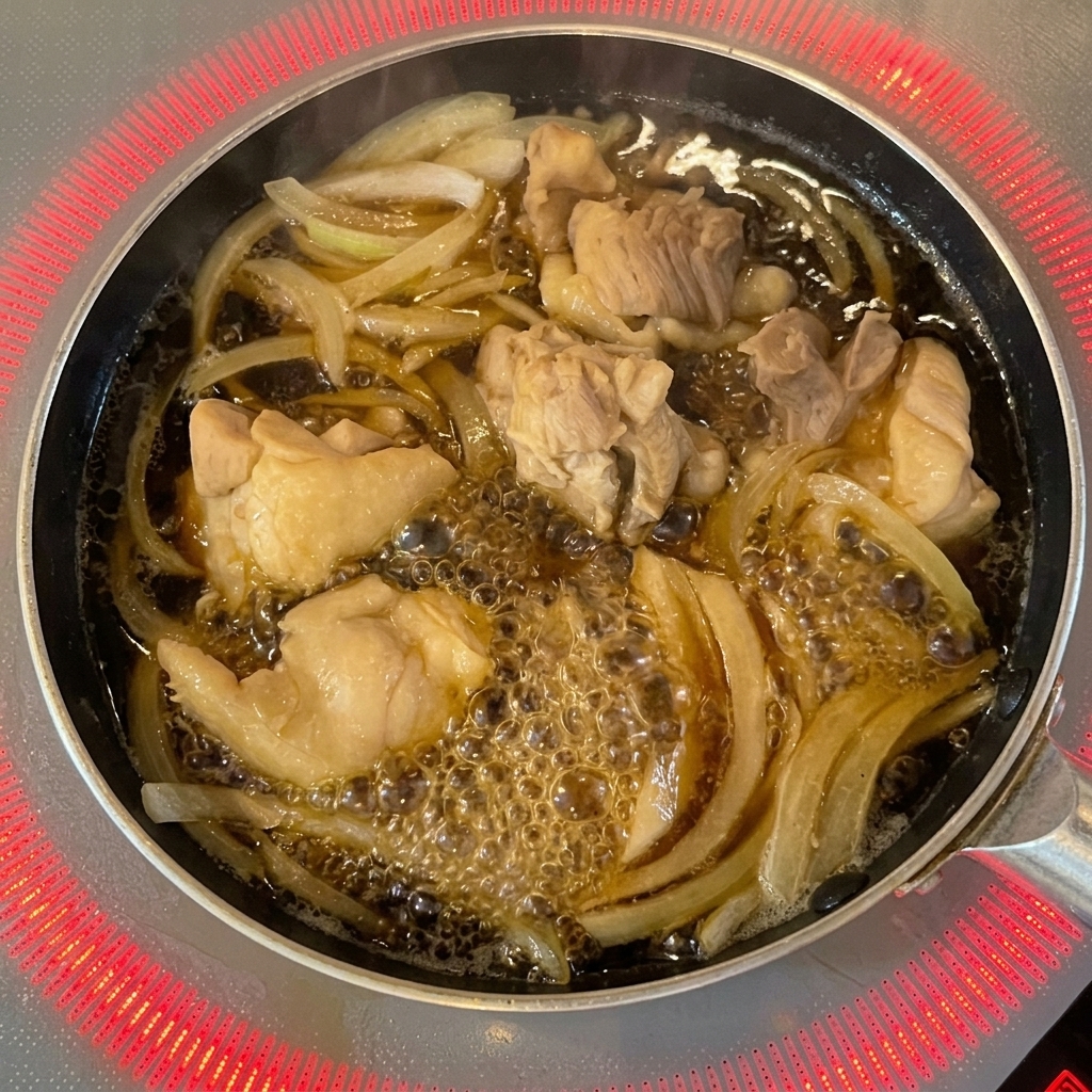 Des œufs battus sont versés depuis un bol dans une poêle sur le poulet et les oignons.