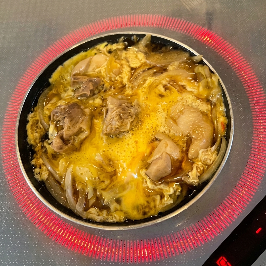 Des feuilles de mitsuba vert frais sont parsemées sur lœuf partiellement cuit et le poulet.