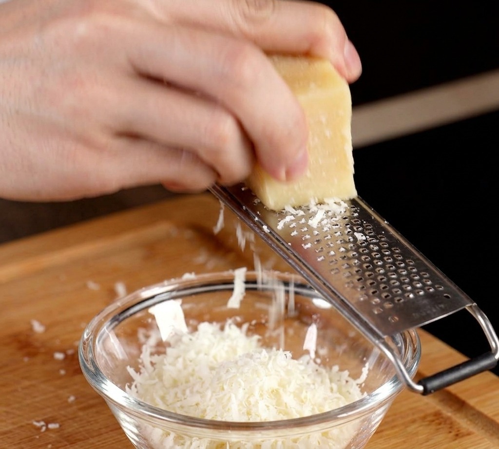 Râper un bloc de parmesan dans un petit bol contenant un jaune dœuf cru.
