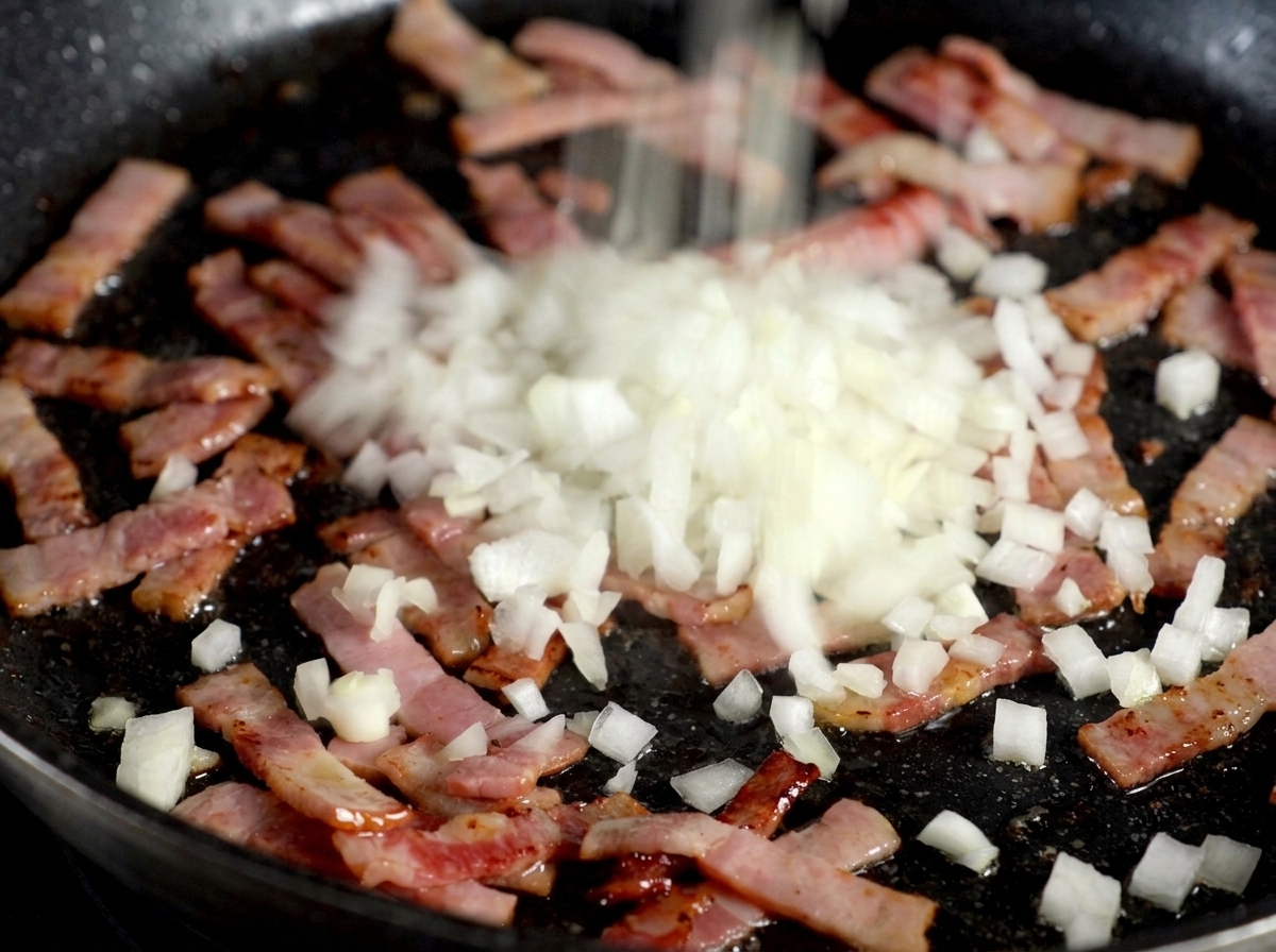 Oignons blancs émincés saupoudrés sur une poêle de lardons grillés crépitants.