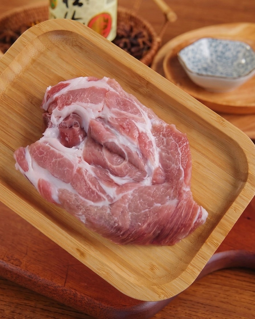 Un morceau déchine de porc crue aplati reposant sur un plateau en bois après avoir été attendri.