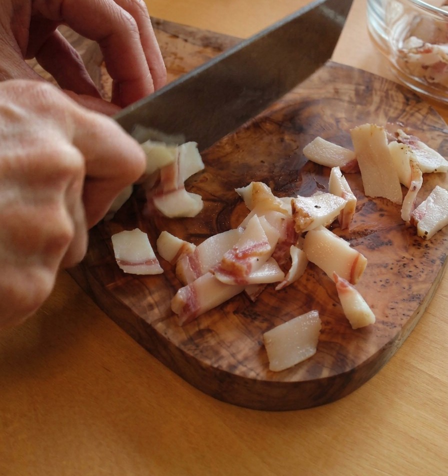 Découpe du guanciale en petites lanières rectangulaires montrant les couches de gras blanc et de viande rosée.