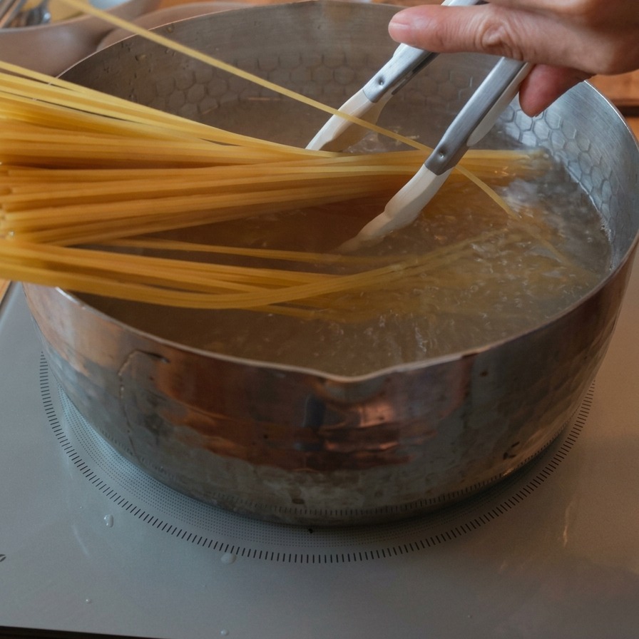 Une botte de spaghettis secs plongée dans une casserole deau bouillante à laide dune pince.
